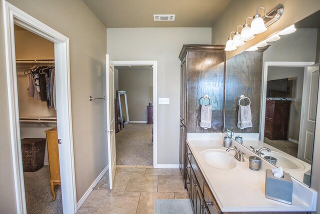 bathroom featuring a walk in closet, vanity, visible vents, and baseboards