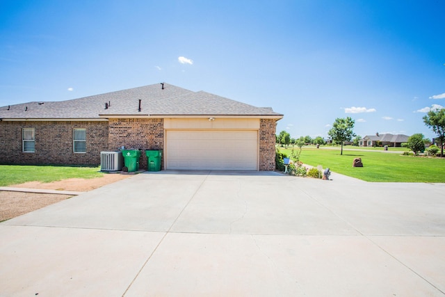 view of side of property with brick siding, a yard, driveway, and central AC