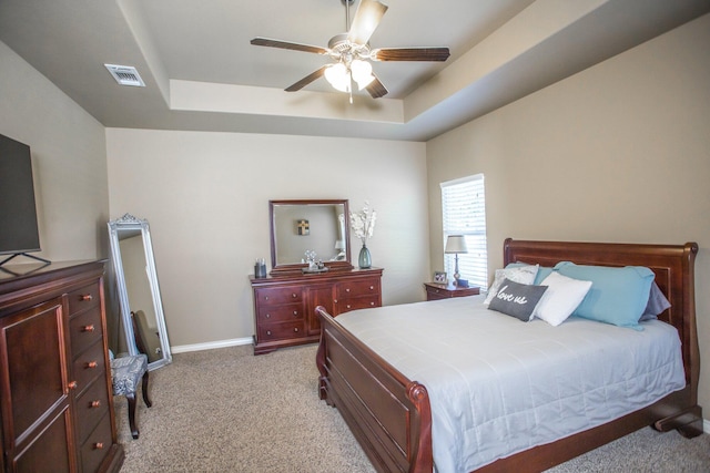 bedroom with visible vents, light colored carpet, and a raised ceiling