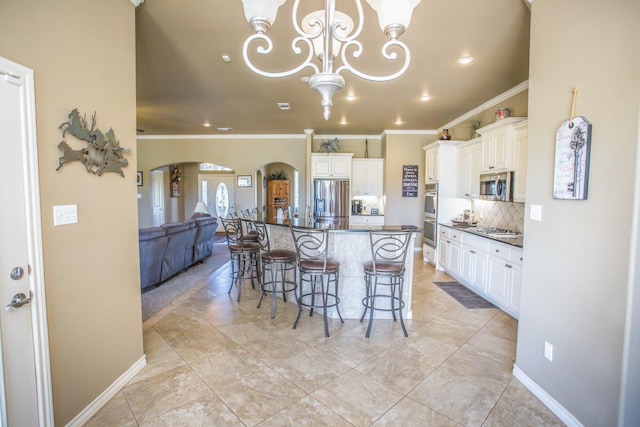 kitchen featuring ornamental molding, dark countertops, arched walkways, and stainless steel appliances