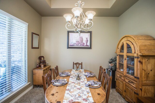 carpeted dining room featuring an inviting chandelier, baseboards, and plenty of natural light