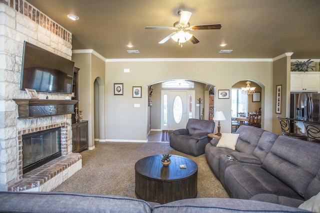 living area with ornamental molding, carpet floors, arched walkways, and ceiling fan with notable chandelier