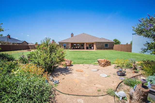 rear view of house with a yard, a fenced backyard, a patio, brick siding, and a chimney