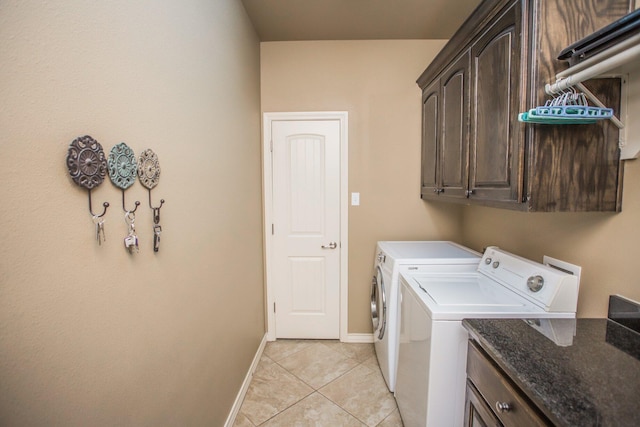laundry room with light tile patterned floors, washer and clothes dryer, baseboards, and cabinet space