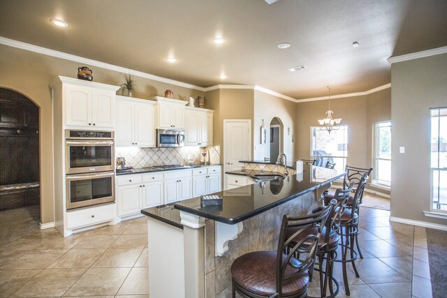 kitchen featuring tasteful backsplash, a chandelier, dark countertops, stainless steel appliances, and a sink
