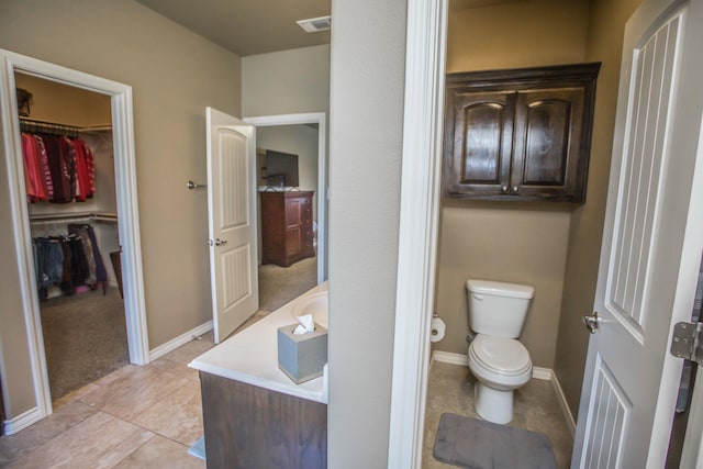 full bathroom featuring visible vents, baseboards, a spacious closet, toilet, and tile patterned flooring