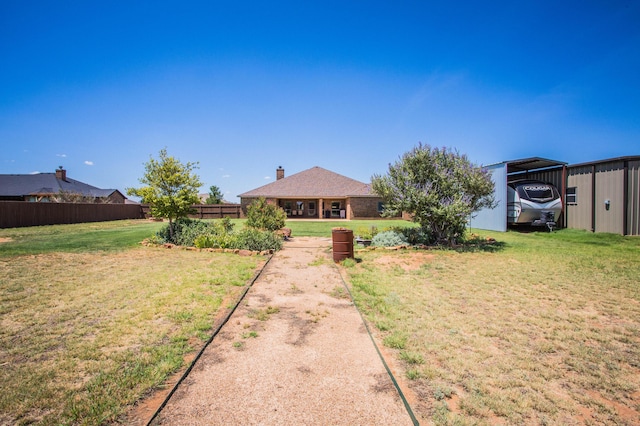 view of front of home featuring a front yard, a carport, fence, and a chimney