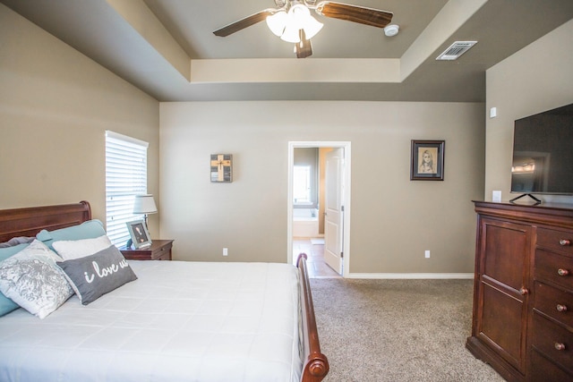 bedroom with visible vents, a tray ceiling, baseboards, and carpet floors