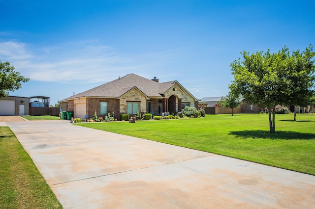 view of front of home featuring stone siding, a garage, fence, a front lawn, and driveway
