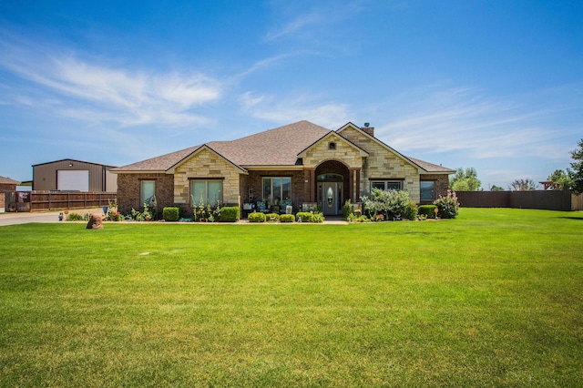 view of front of property with fence, a front yard, stone siding, and a chimney