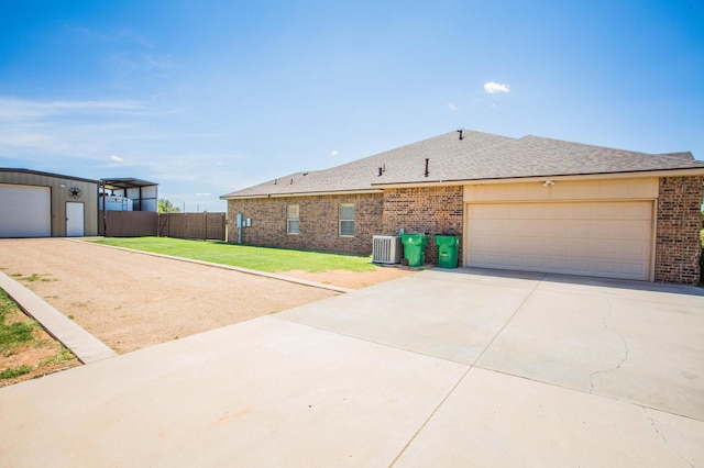view of front facade with cooling unit, fence, a front lawn, brick siding, and concrete driveway