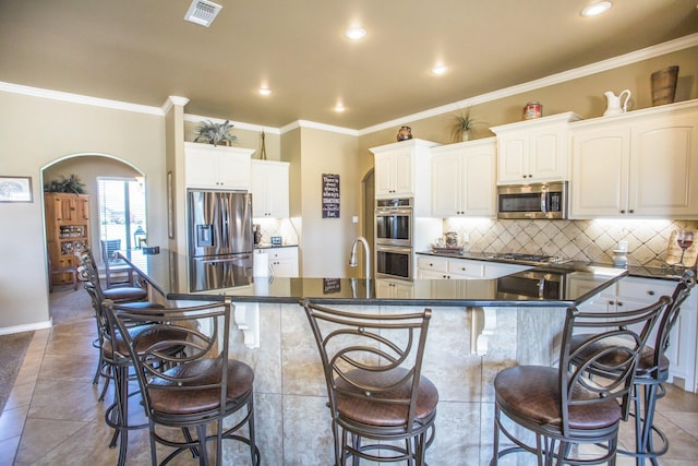 kitchen with recessed lighting, dark countertops, a breakfast bar, and appliances with stainless steel finishes