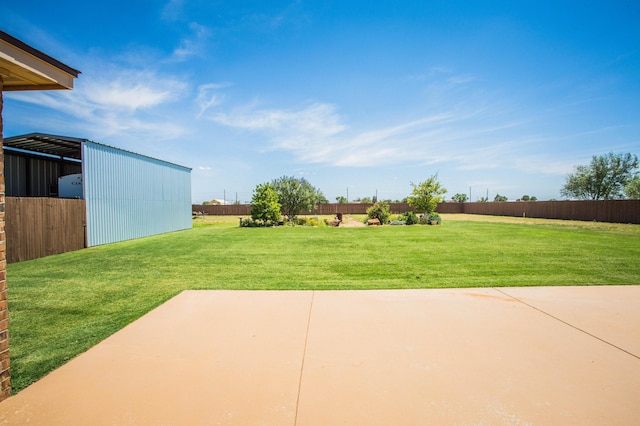 view of yard featuring a patio area, fence, and an outbuilding