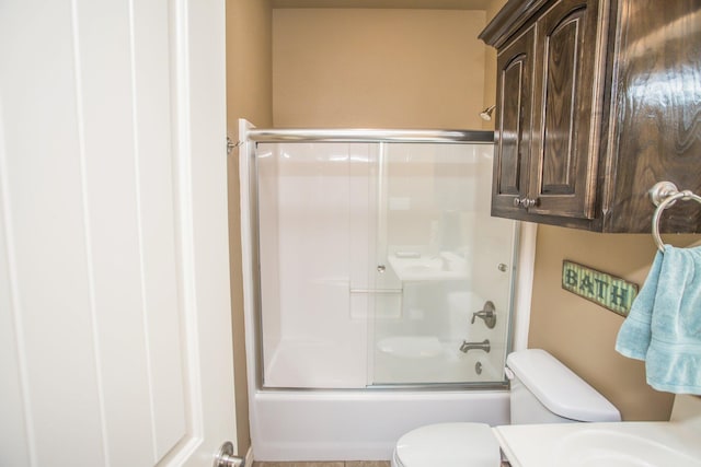 bathroom with toilet and shower / bath combination with glass door