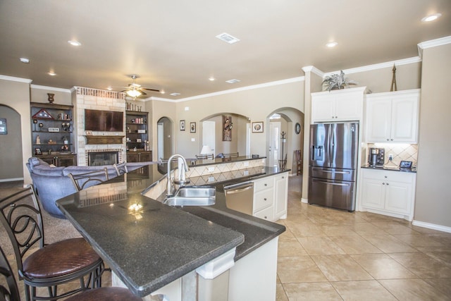 kitchen with arched walkways, a sink, ceiling fan, stainless steel appliances, and decorative backsplash