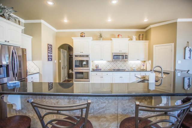 kitchen with a sink, white cabinets, a breakfast bar area, and stainless steel appliances