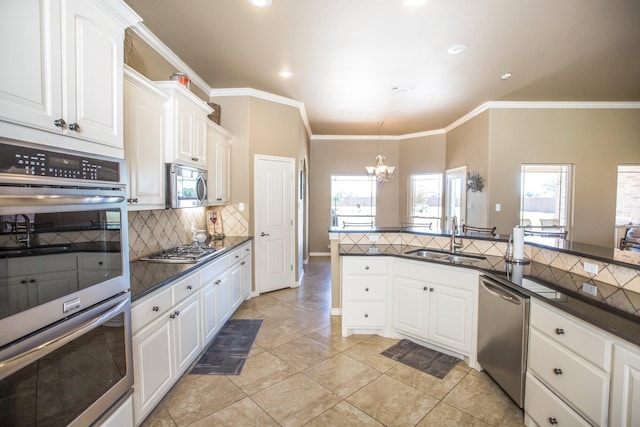 kitchen featuring tasteful backsplash, a sink, appliances with stainless steel finishes, dark countertops, and a chandelier