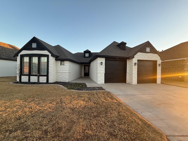 view of front facade with a garage, concrete driveway, stone siding, roof with shingles, and a front lawn