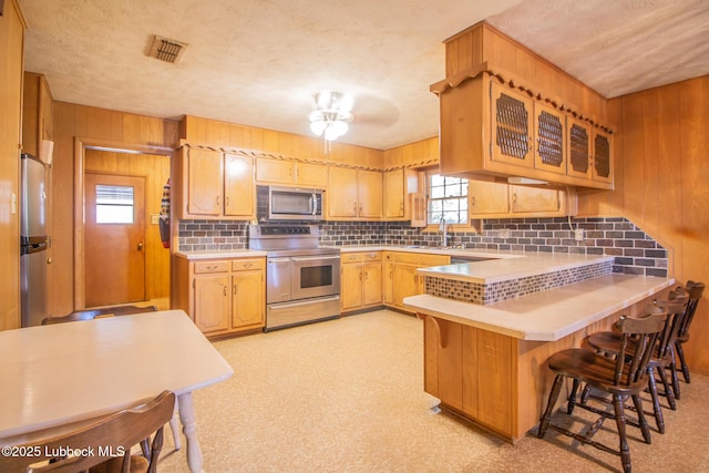 3404 59th St, Lubbock, TX 79413 - kitchen with stainless steel appliances, a sink, tasteful backsplash, a peninsula, and light countertops