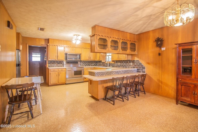 3404 59th St, Lubbock, TX 79413 - kitchen with stainless steel appliances, light countertops, a peninsula, wooden walls, and a sink