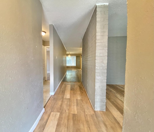 hallway featuring light hardwood / wood-style floors and a textured ceiling