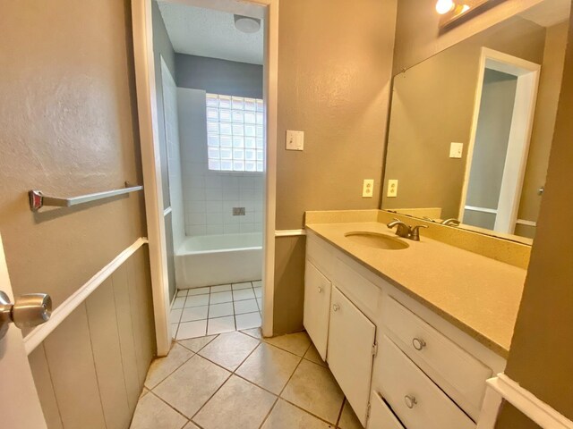 bathroom featuring tile patterned flooring, vanity, and tiled shower / bath