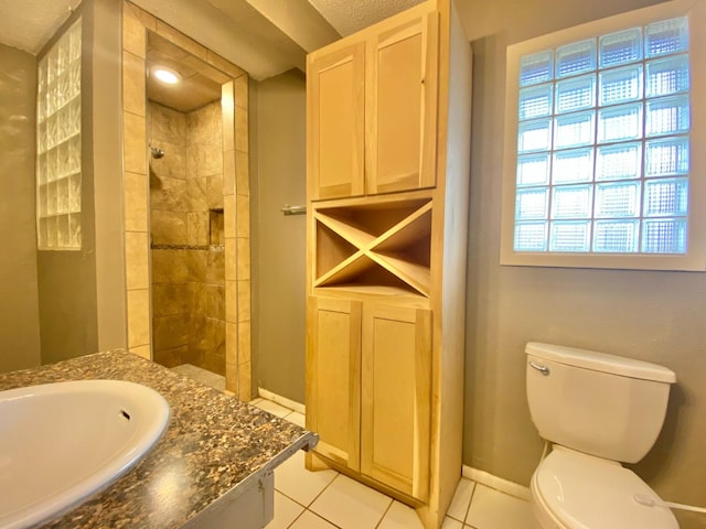 bathroom with toilet, tile patterned floors, a textured ceiling, a tile shower, and vanity