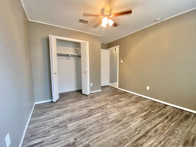 unfurnished bedroom with hardwood / wood-style floors, ceiling fan, a textured ceiling, and a closet