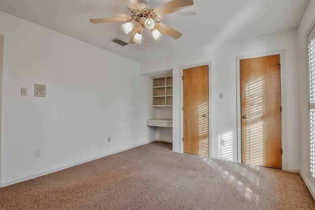 unfurnished bedroom featuring built in desk, carpet floors, and ceiling fan