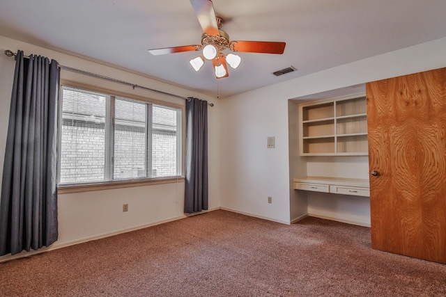 unfurnished bedroom featuring ceiling fan, built in desk, and carpet floors