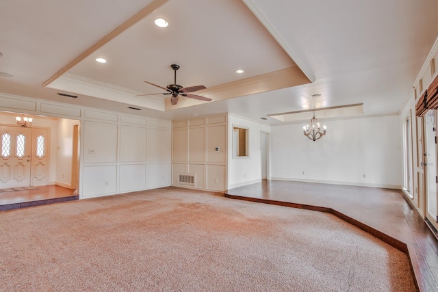 unfurnished living room with carpet flooring, ornamental molding, a tray ceiling, and ceiling fan with notable chandelier