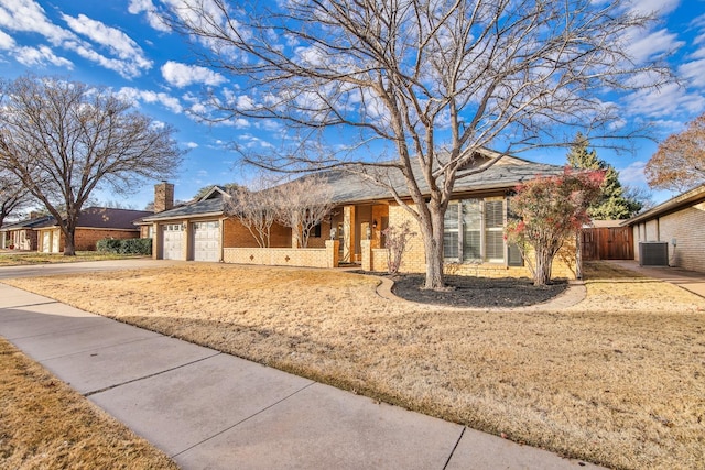 ranch-style home featuring central AC, a garage, and a front lawn