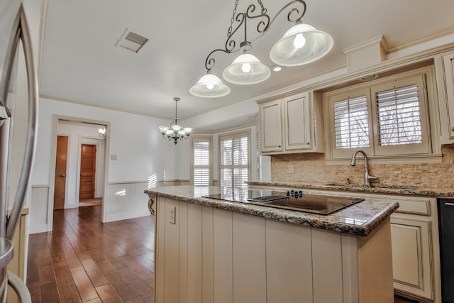 kitchen with sink, stone counters, a center island, cream cabinets, and black appliances