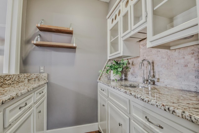 kitchen featuring tasteful backsplash, sink, white cabinets, and light stone counters