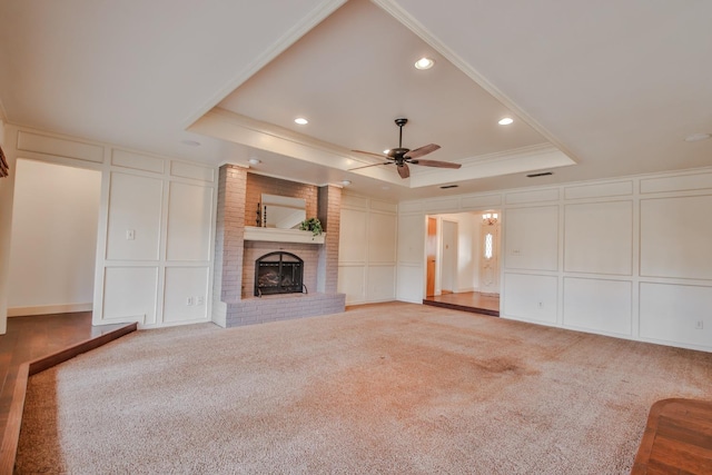 unfurnished living room featuring a fireplace, a raised ceiling, and carpet