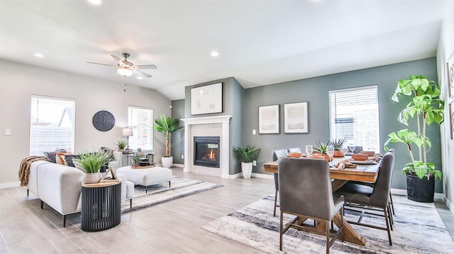 living room with ceiling fan, lofted ceiling, light wood-type flooring, and a wealth of natural light