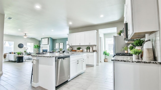 kitchen with stainless steel appliances, a kitchen island with sink, sink, and white cabinets