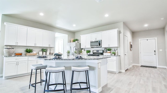 kitchen with a center island with sink, white cabinets, and appliances with stainless steel finishes