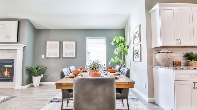 dining space featuring a brick fireplace and light hardwood / wood-style flooring