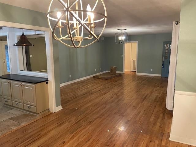 unfurnished dining area featuring a notable chandelier and wood-type flooring