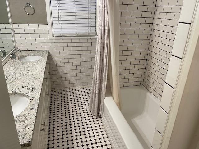 bathroom with tile patterned flooring, vanity, tile walls, and shower / bath combo with shower curtain