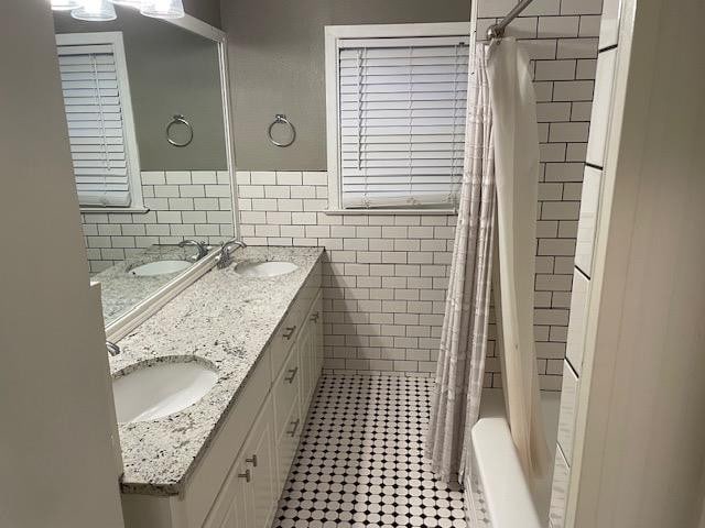 bathroom with tile patterned flooring, vanity, tile walls, and shower / tub combo with curtain