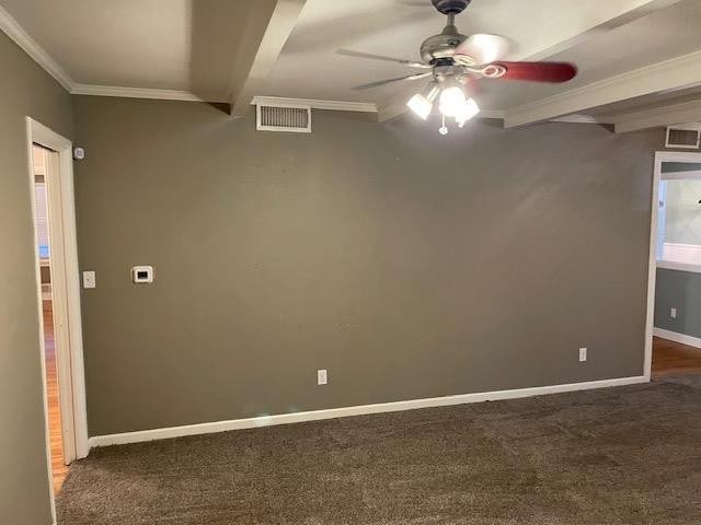 unfurnished room with beam ceiling, ornamental molding, ceiling fan, and dark colored carpet