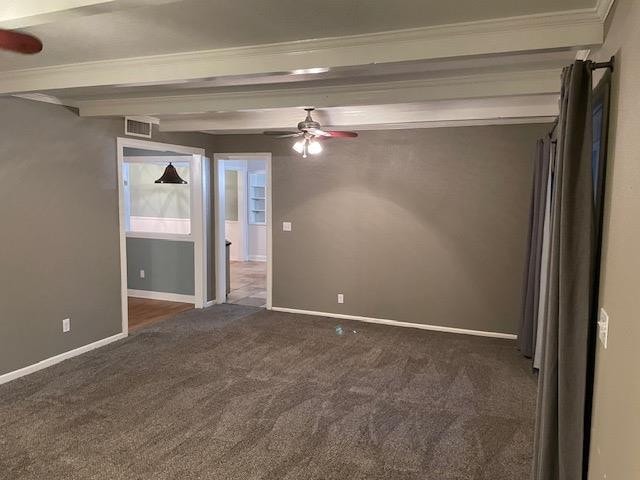 unfurnished room featuring beamed ceiling, ceiling fan, and dark carpet