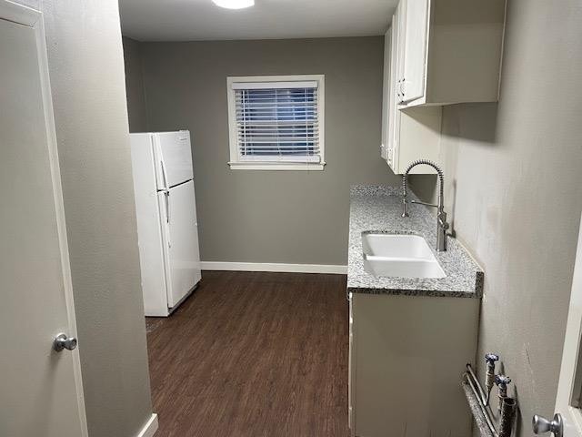 kitchen with white refrigerator, light stone countertops, sink, and dark hardwood / wood-style flooring