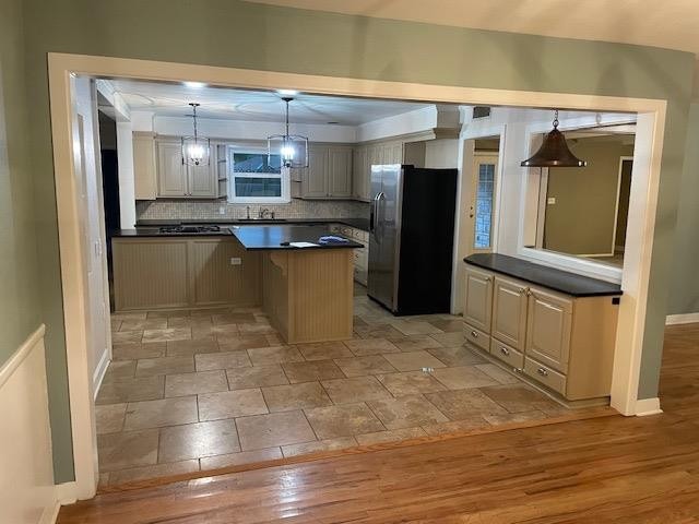 kitchen featuring sink, tasteful backsplash, stainless steel fridge with ice dispenser, hanging light fixtures, and light wood-type flooring