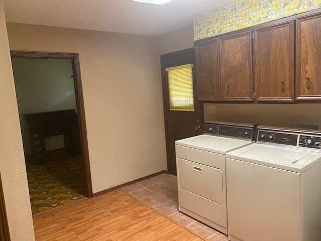 laundry room with washing machine and dryer, cabinets, and light wood-type flooring