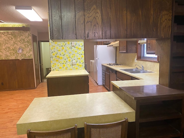 kitchen with dark brown cabinetry, sink, white appliances, and light wood-type flooring