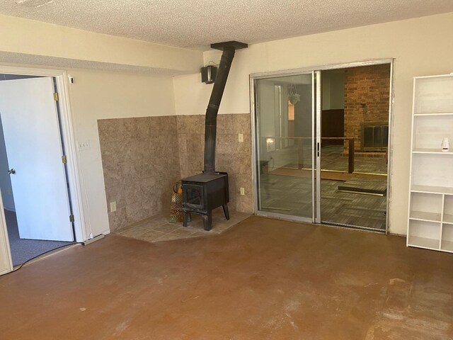unfurnished living room with concrete floors, a textured ceiling, and a wood stove