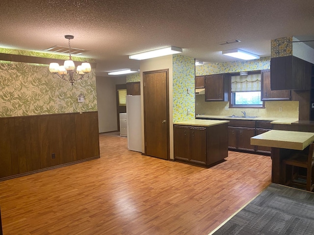 kitchen with pendant lighting, sink, dark brown cabinets, and a textured ceiling